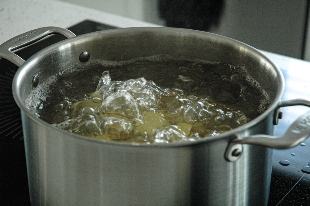 parboiling yellow potatoes in a stock pot of salted boiling water