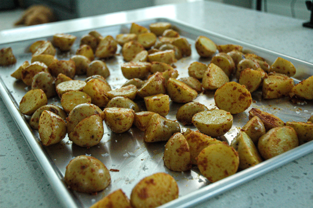 seasoned parboiled potatoes on a baking sheet and ready for the oven